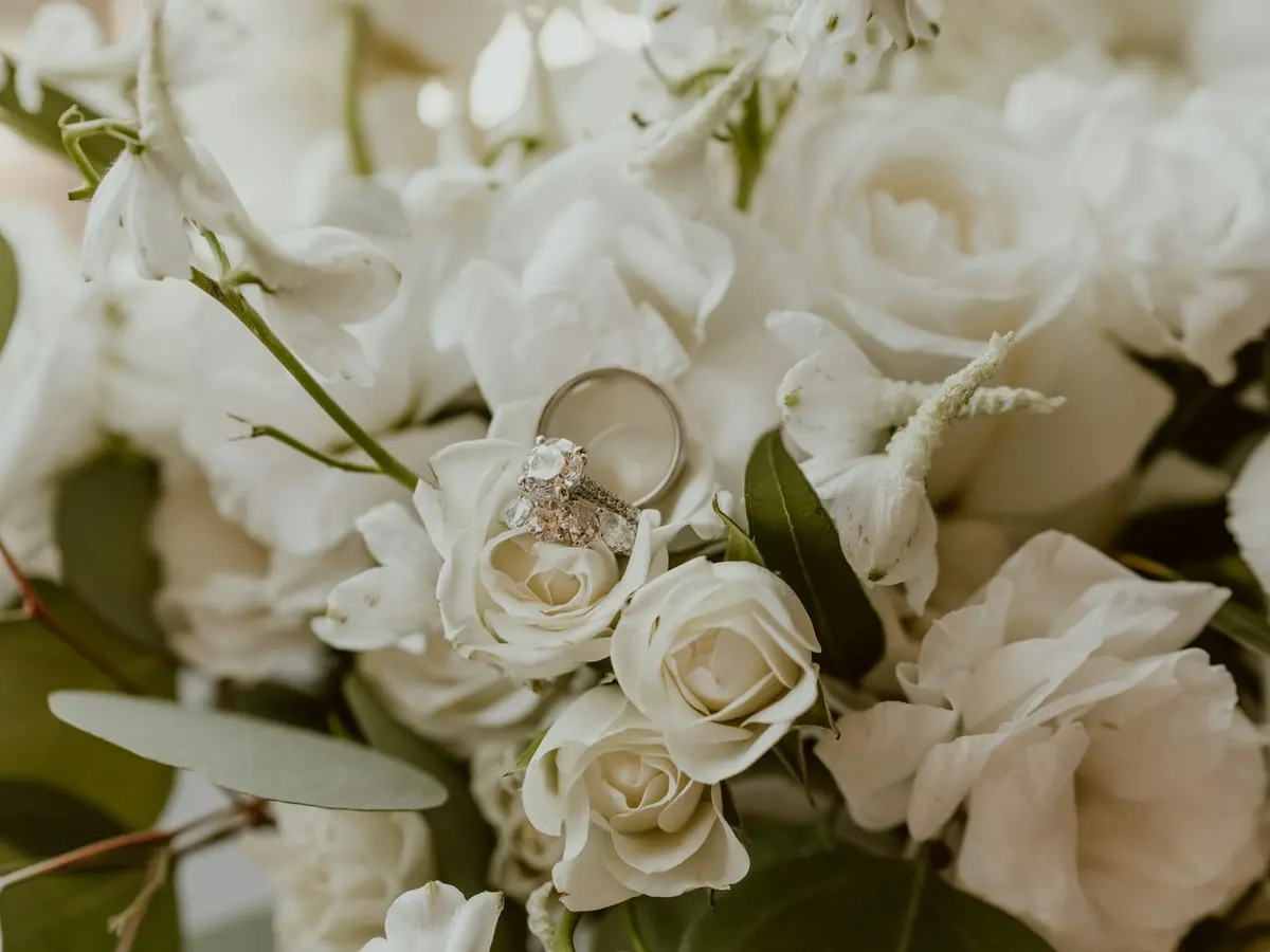 Zwei Eheringe auf weißen Rosen
