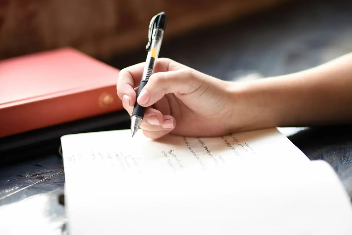 Eine Hand schreibt mit Kugelschreiber in ein Notizbuch