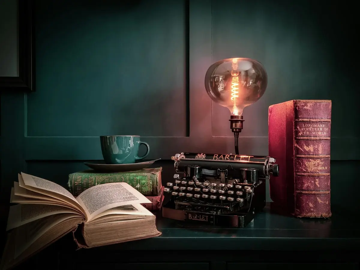 Alte Schreibmaschine mit Lampe und Büchern auf einem Schreibtisch